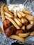 Currywurst & Pommes: Famous German Fast Food Curry Sausage with French Fries and Curry Sauce on aluminium foil