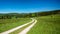Curve on unpaved route on a mountain meadow leading towards a forest in a colorful hilly landscape, Krkonose mountains, Czech