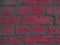 Curved brickwork of bright pink crimson geometric horizontal bricks bonded with cement grout between square stones