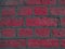 Curved brickwork of bright pink crimson geometric horizontal bricks bonded with cement grout between square stones. Wall
