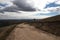 Curved Dirt Road on Hilltop Surrounded by Bleak Landscape