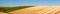 Curved lines of a ploughed field with a blue sky and white fluffy clouds of the rolling farmland in Sussex, England, UK