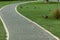 Curved paved pathway in a park with ducks resting aslongside
