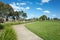 A curved pedestrian footpath/walkway in a suburban park with some modern Australian homes/houses in the distance. Background