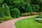 Curved pedestrian pavement of stone tiles in park with slope landscape.