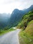 Curved road surrounded by mountains with lonely motorbike in the distance