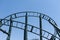 Curved Rollercoaster at a theme or amusement park empty green metal tracks and on blue sky background