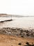 Curved seaside scene pipe groyne beach seaweed pebbles