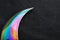 The curved sharp blade of the Kerambit Dagger is a gradient rainbow color on a dark background.