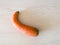 Curved withered carrot isolated on wood texture background, shrivel inedible overripe vegetable, food decay concept