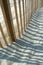 Curved wooden beach fence shadows on sand