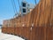 Curved wooden fence with warning signs blocking off dangerous wires