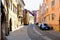 Curving old classic narrow alley street with cobblestone pavement and parked cars