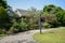 Curving path and grassy lawn before woody houses in sunny summer