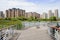 Curving planked footbridge over lake in modern city on sunny sum