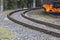 Curving railway tracks on crushed stone and orange train, telephoto