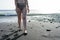 Curvy adolescent walking in the beach in the sunset in the wet black sand and waves on the sea. Caucasian woman in bikini at the