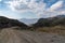 Curvy dirt road leading down to a secluded beach on a wild and mountainous coastline