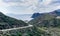 Curvy dirt road leading down to a secluded beach on a wild and mountainous coastline