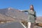 Curvy Energetic white skin tourist lady, hitch hiking in the volcano of el Teide, Tenerife, with a green dress showing legs.