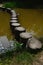 Curvy pathway through the muddy decorative pond made of barrel shaped stone columns