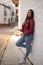 Curvy pretty girl looking with smartphone in her hand next to a peculiar white wall in the street