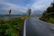 Curvy road across mountains, road mirror, and cloudy sky. Transportation infrastructure. Movement, travel, ride, drive concept