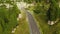 Curvy road in highland passes through coniferous forests. Aerial view showcases white car on scenic serpentine freeway