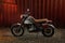 Custom scrambler motorbike on a rusty container background.