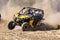 Custom twin seater rally buggy kicking up trail of dust on sand