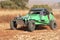 Custom twin seater rally buggy kicking up trail of dust on sand