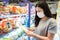 Customer Asian Woman Wearing Face Mask With Shopping Cart in Supermarket Department Store Shop While Choosing and Looking Goods on