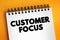 Customer Focus - strategy that puts customers at the center of business decision-making, text concept on notepad