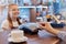 Customer paying through mobile phone over electronic reader in coffee shop, faceless customer holding card, smiling red haired