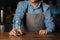 Customer service in pub. Barman gives empty glass to client on wooden bar counter