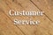 `Customer Service` white text on a wooden background.