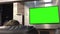 A customer sitting on the sofa and watching display tv with a green screen inside the electrical store