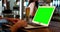 Customer using a laptop with green screen at bar counter