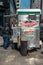 Customers along side a food cart selling cheesestakes and kabobs on a city street at lunchtime