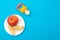 A cut apple on a plate and a baby nibbler on a blue background. The concept of feeding children fruits and vitamins