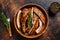 Cut BBQ grilled pork rack spareribs in a wooden plate. Dark background. Top view