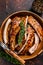 Cut BBQ grilled pork rack spareribs in a wooden plate. Dark background. Top view