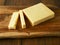 Cut block of red cheddar on a wooden cutting board and table. Premium high quality dairy product for many cooking applications.