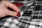 Cut the checkered fabric. Scissors on black and white fabric. Female hand with a red manicure