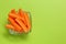 Cut fresh carrot in bowl and space for text on green background, top view. Finger food