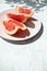 Cut grapefruit slices on pink plate on marble table with selective focus and copy space, vertical. Fresh citrus