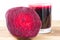 Cut half beetroot and fresh beet juice in glass on wooden table, white background.