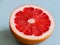 Cut in half the fruit pink grapefruit in a neutral blue surface