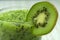 Cut kiwi in a glass on the kitchen table. Finely chopped kiwi slices and whole kiwi in the kitchen.