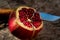 Cut open Pomegranate showing colouful seeds on rustic wooden table with french folding Knife